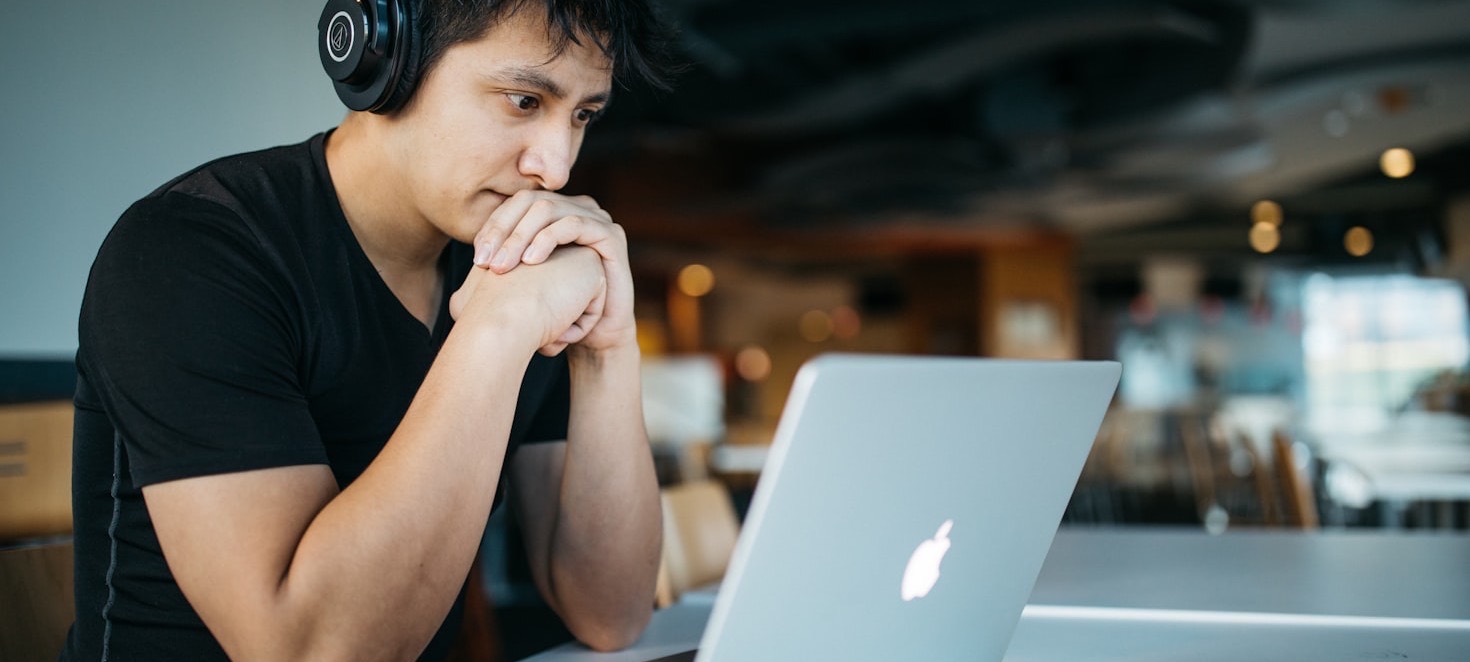 A student sitting with a laptop in a cafe, working through a station.